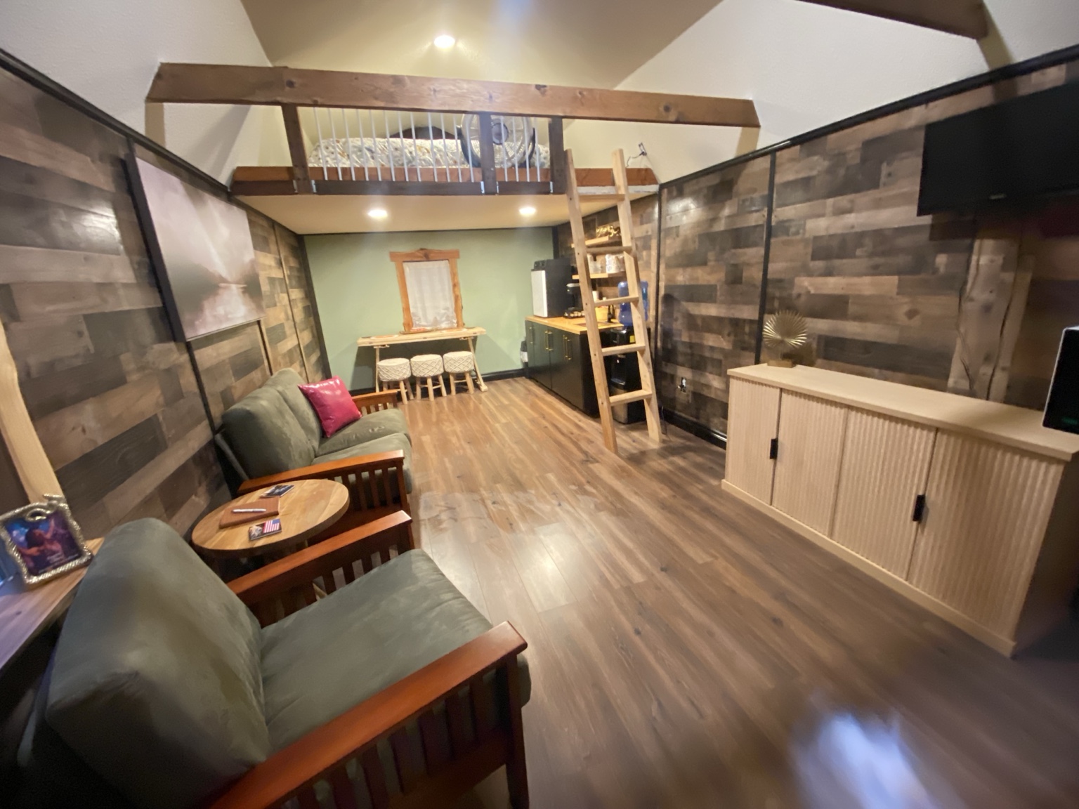 Open downstairs living room with seating, kitchenette and queen loft above at Castle Rock Mini Lodge